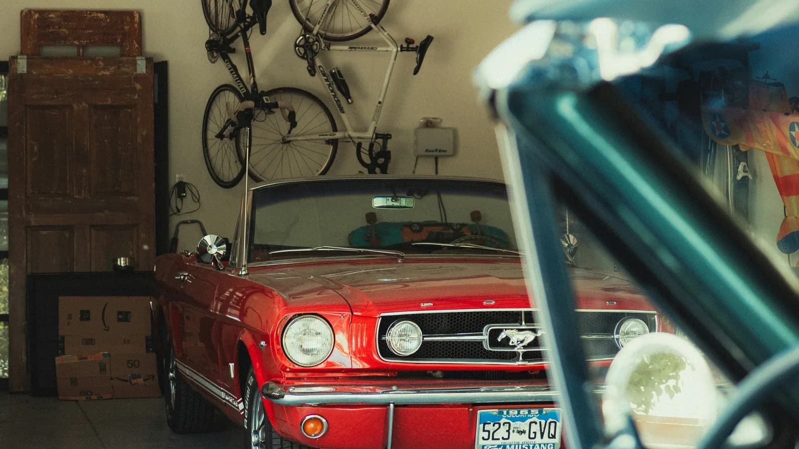 A red classic Mustang convertible parked in a home garage