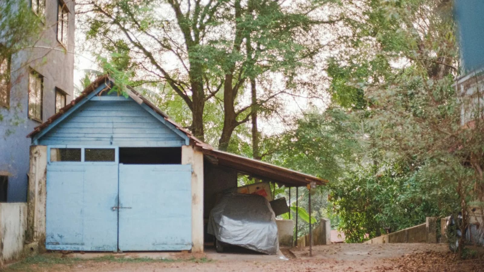 A car under a cover in a garage on private land, off the public road